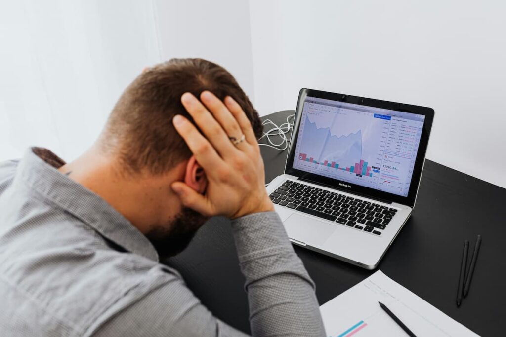 Stressed Bitcoin investor worried about market crash looking at downward trading chart on laptop screen